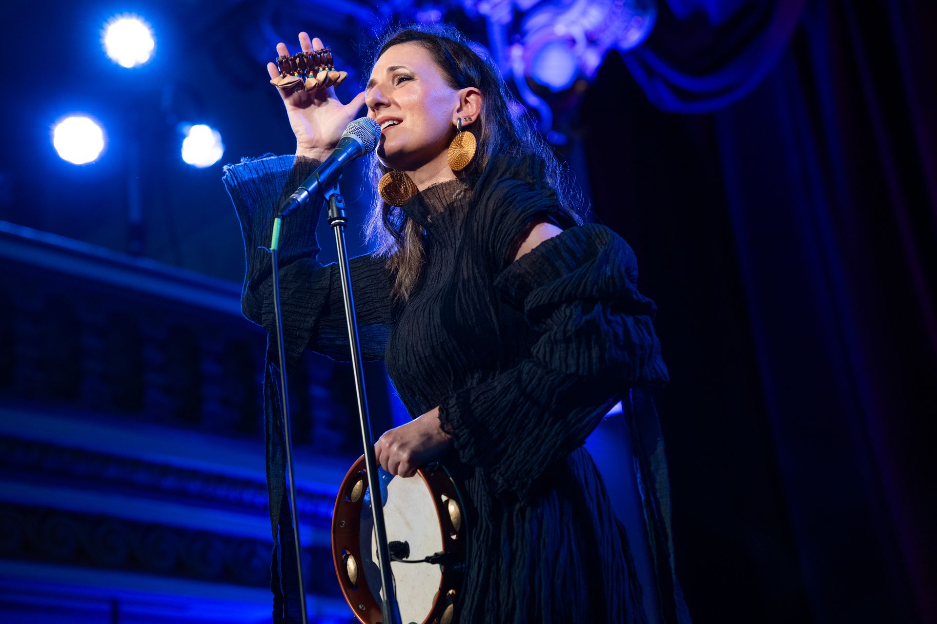 Mara Halunga singing with a tambourine under blue lights